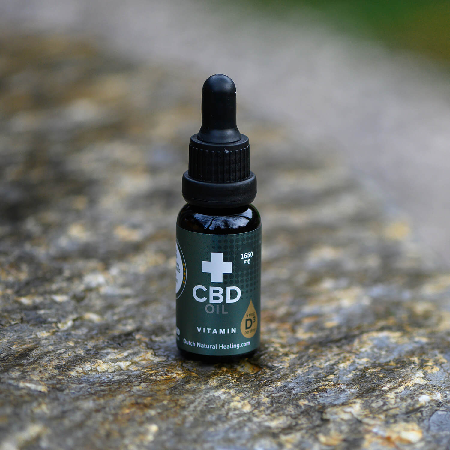 CBD Olie 8% met Vitamine D3 van Dutch Natural Healing, flesje 20 ml op een steen